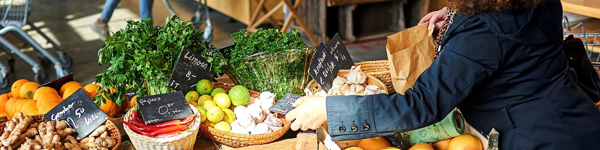 Banner homepage wateetnederland.nl. Vrouw koopt groenten op markt (1920 x 480)