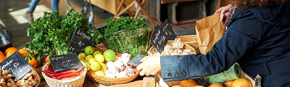 Banner homepage wateetnederland.nl. Vrouw koopt groenten op markt (1920 x 480)